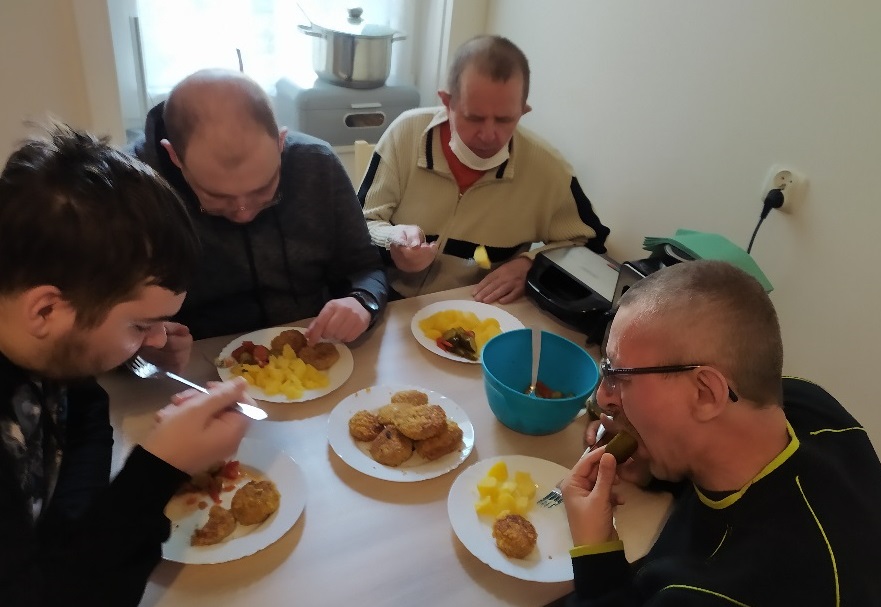 Czterej mężczyźni przy stole  w kuchni  jedzą obiad.