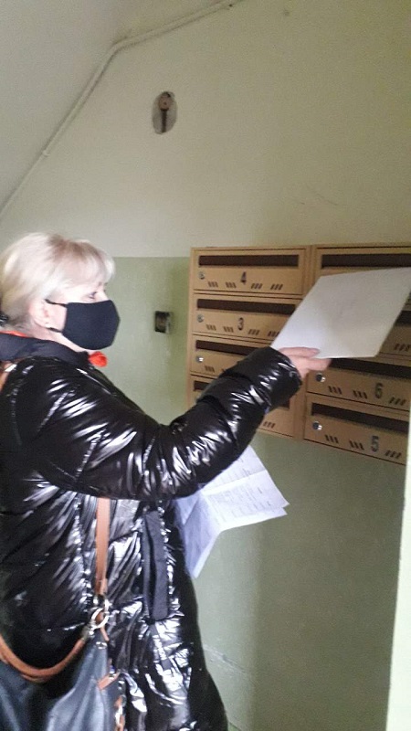 Kobieta wrzuca do skrzynki pocztowej kopertę z zadaniami do samodzielnej pracy w domu. 