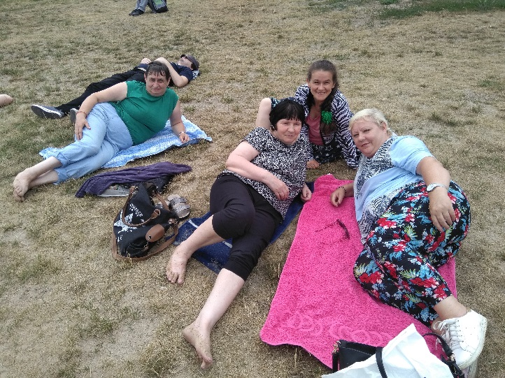 Cztery kobiety i jeden mężczyzna leżą na trawie.