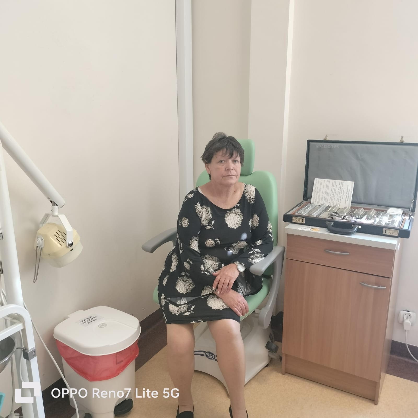 Kobieta siedząca na fotelu do badań lekarskich, w tle przyrządy okulistyczne. 