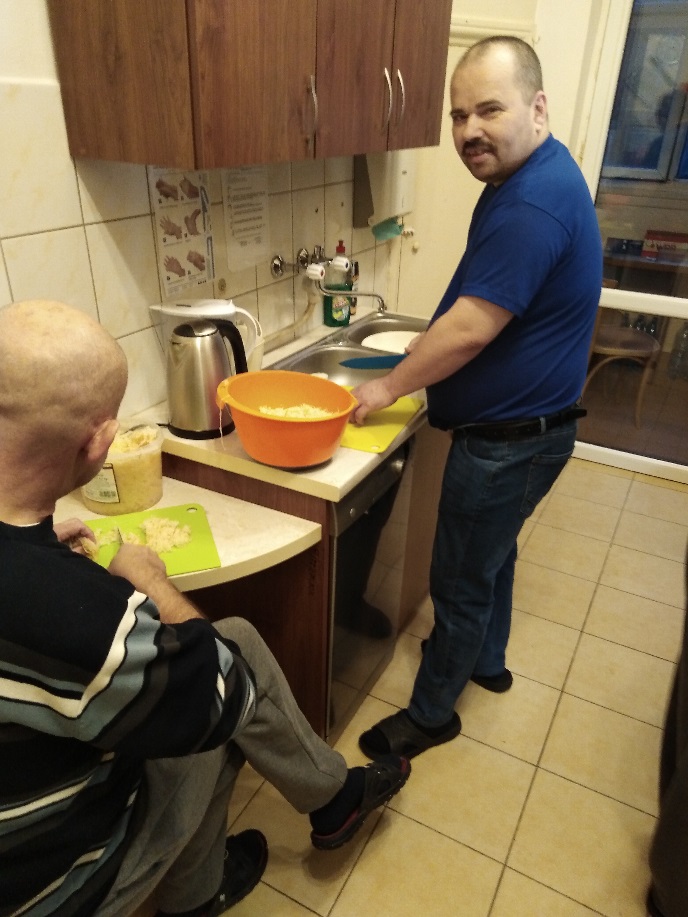 Dwóch mężczyzn kroi w kuchni warzywa.