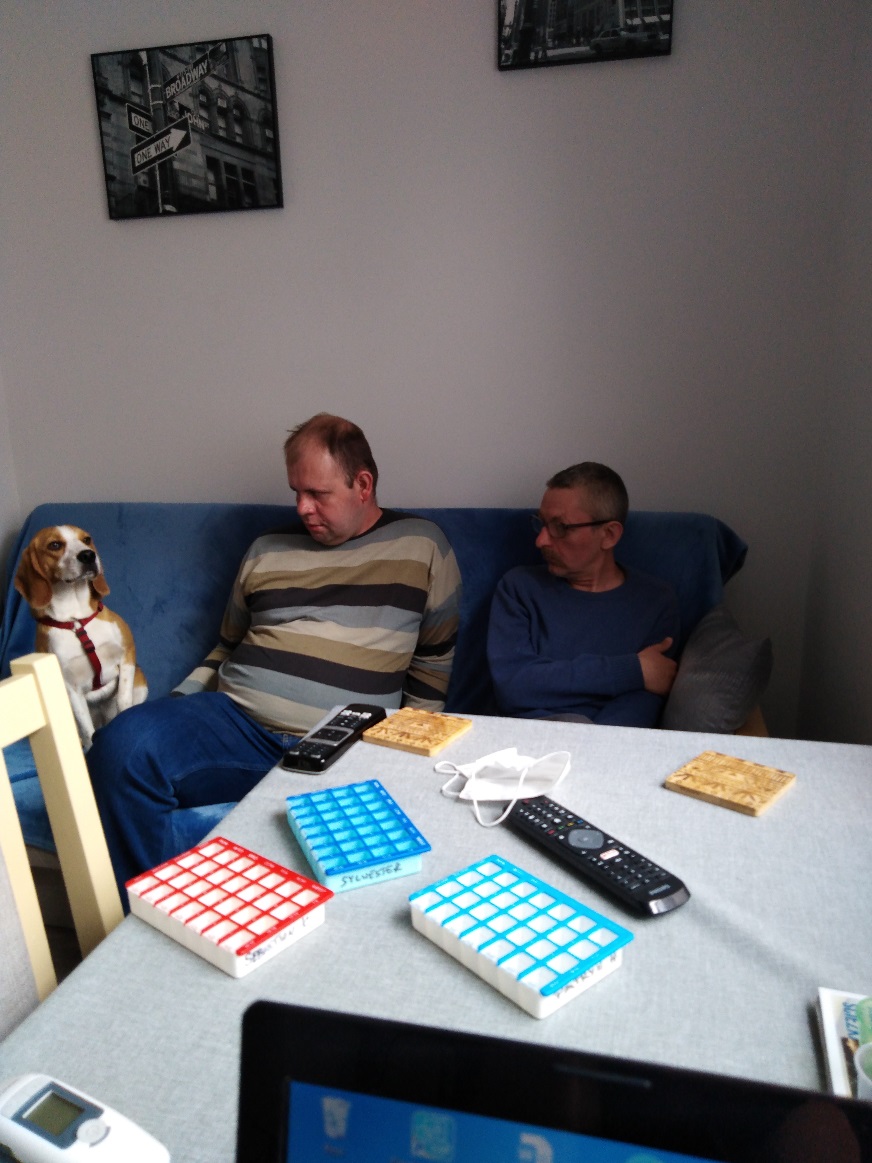 Dwaj mężczyźni siedzą na kanapie razem z psem.