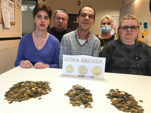 Trzy kobiety i dwóch mężczyzn prezentują drobne złote monety.