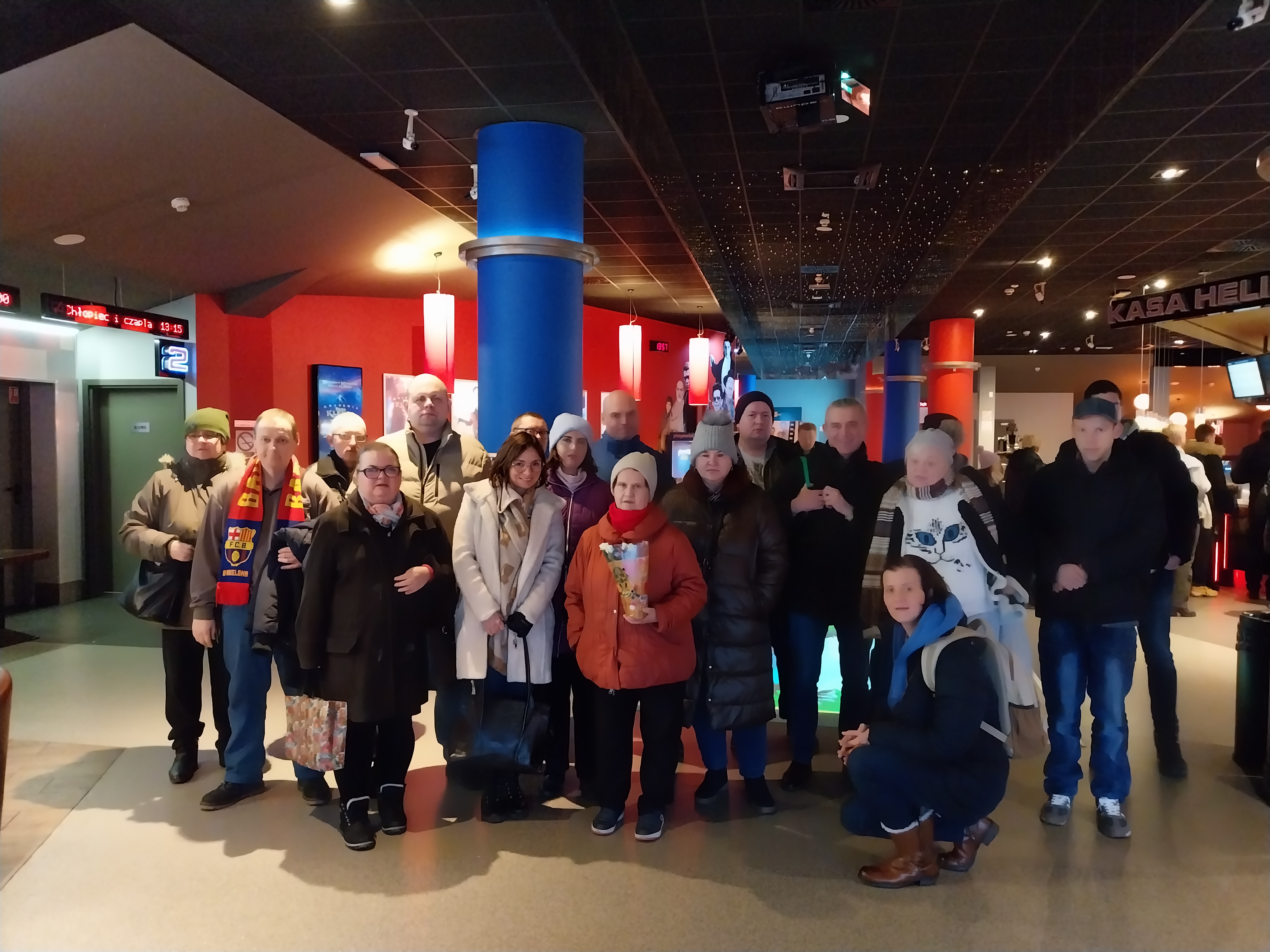 Grupa dwudziestu osób stoi w holu kina i pozuje do zdjęcia. 