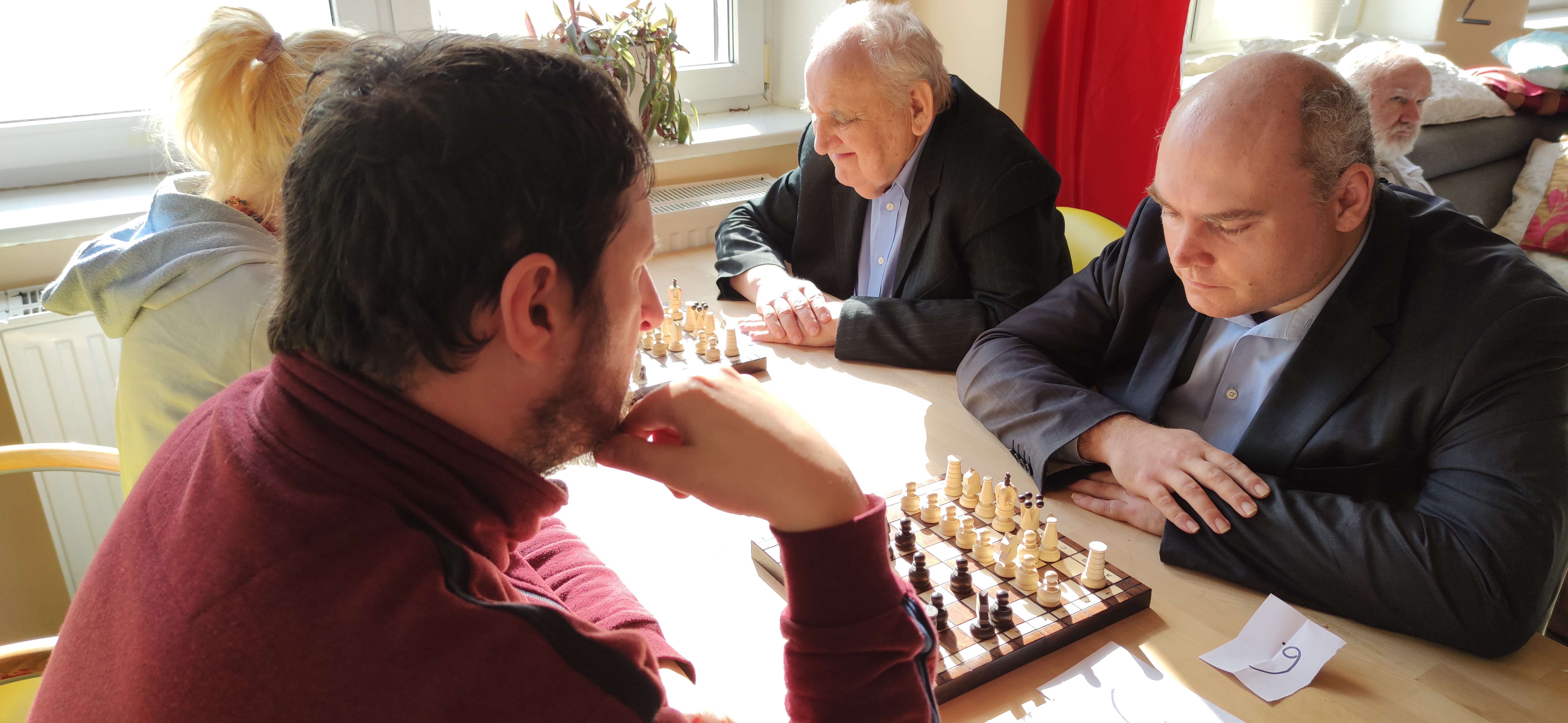 Trzech mężczyzn siedzi przy szachach.