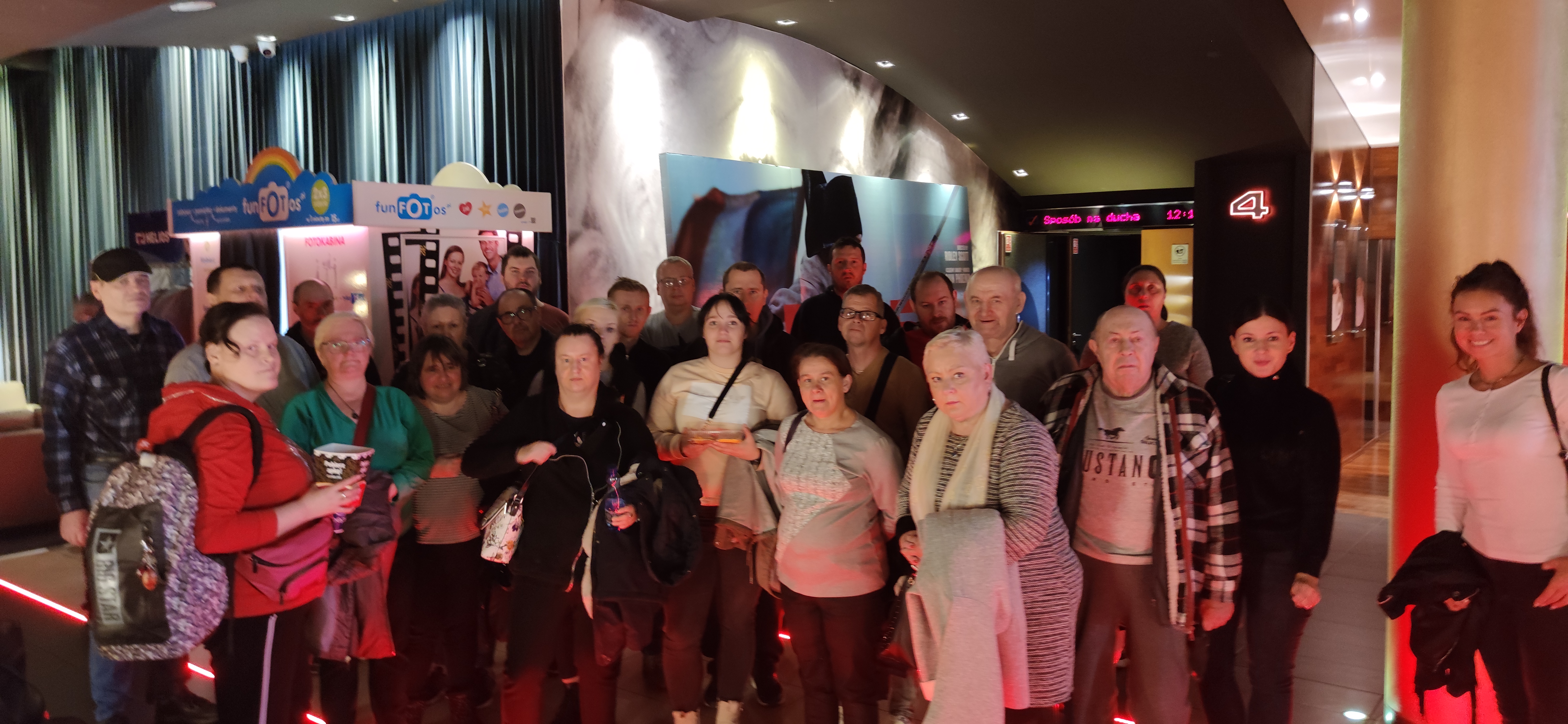 Grupa osób stoi przed wejściem na salę kinową.