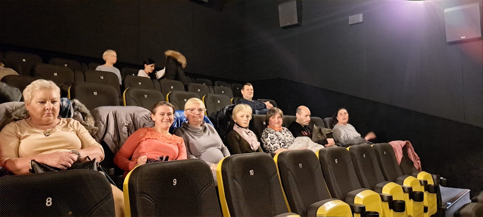 Grupa osób siedzi na sali kinowej .