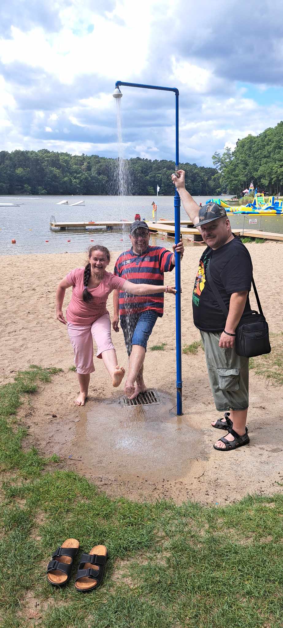 Trzy osoby stoją pod prysznicem nad jeziorem Głębokim.