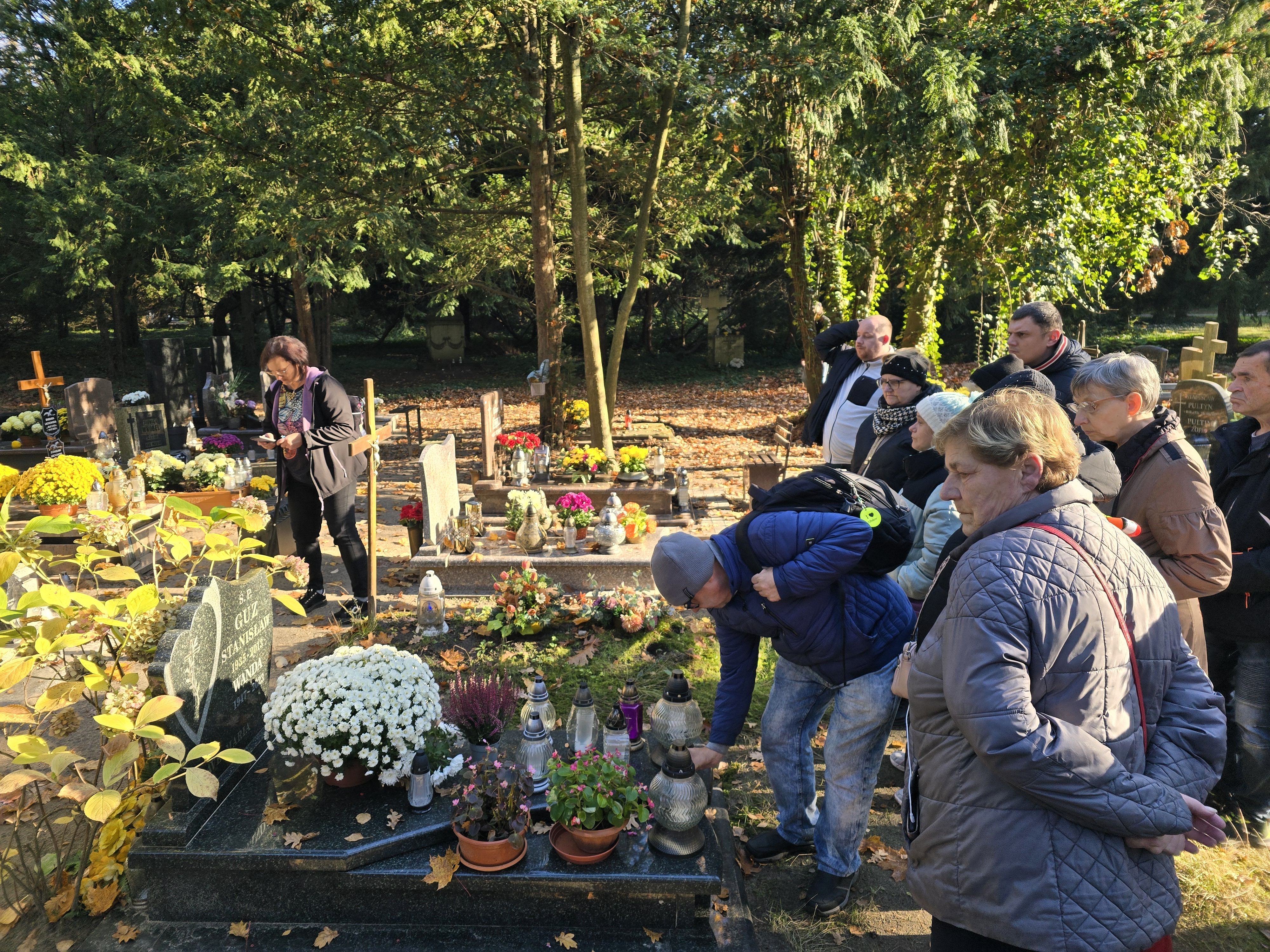 Grupa osób stoi przy grobie.