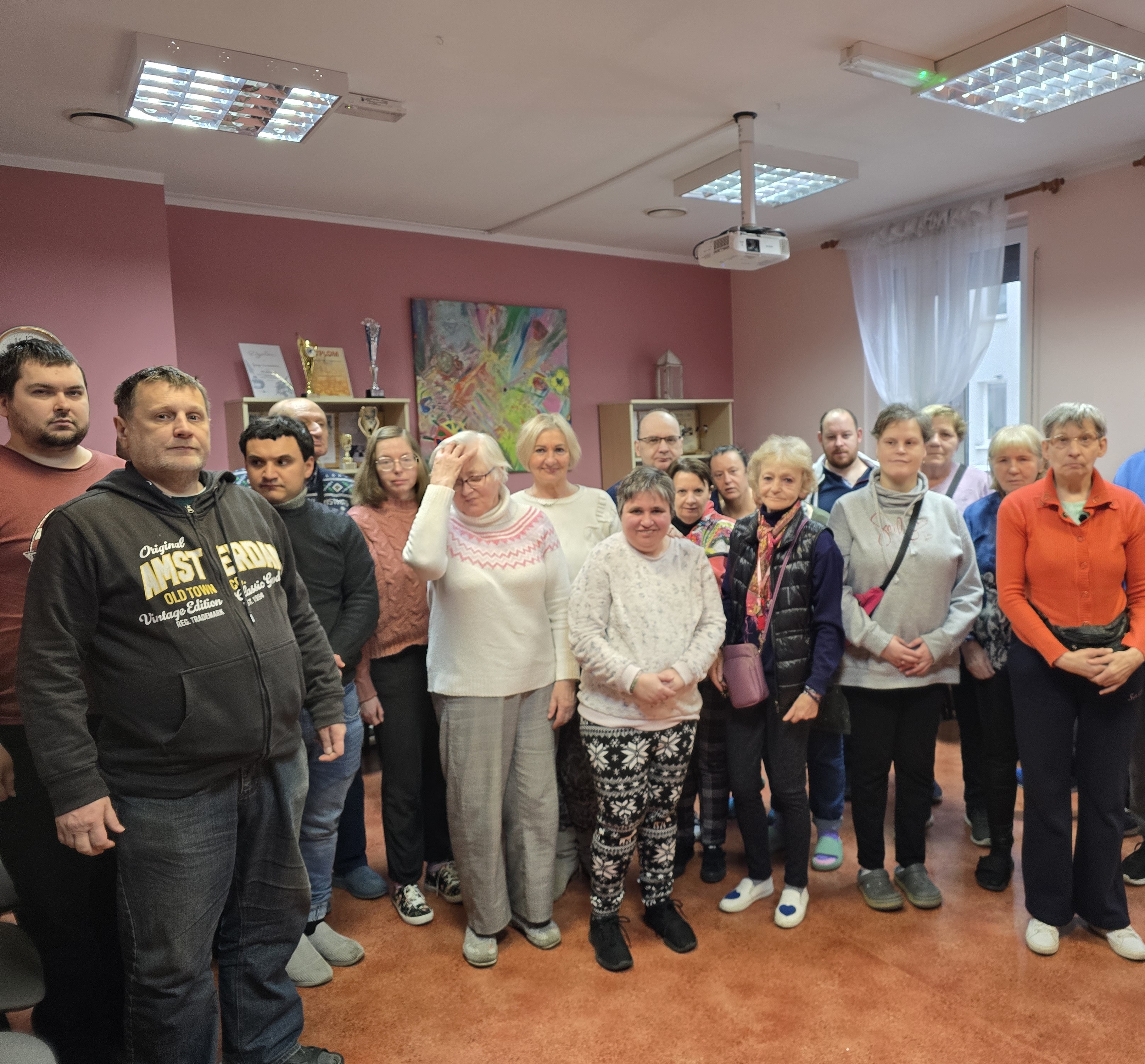 Grupa osób siedzi z prelegentką w dużej sali.