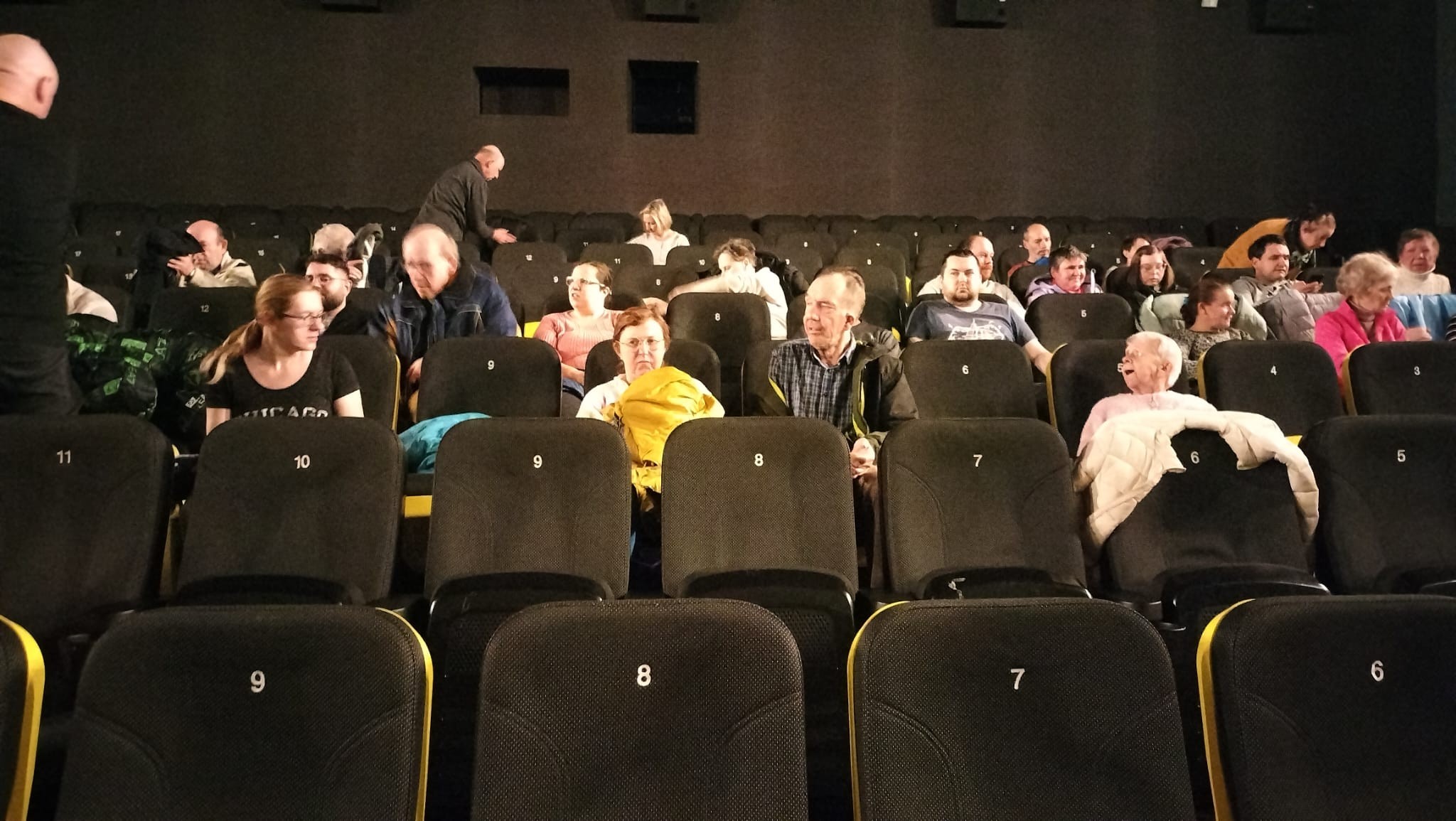 Grupa osób siedzi w kinie.