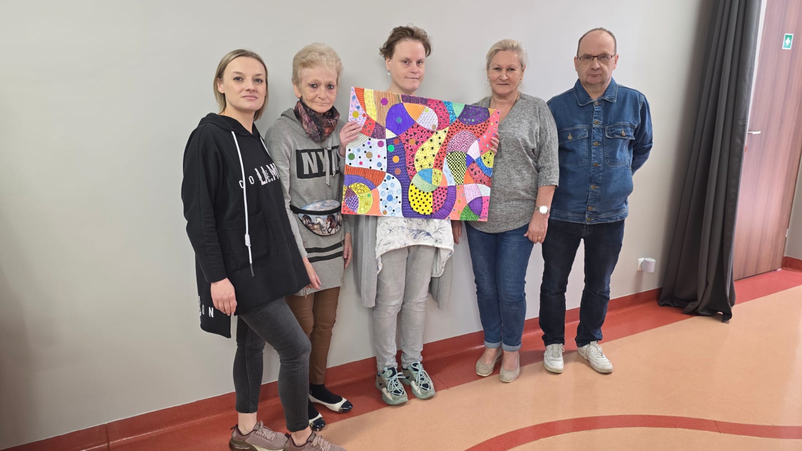 Grupa osób nad kolorową kartką pokrytą rysunkami.