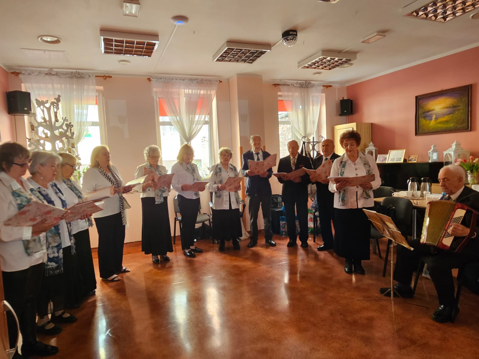 Grupa osób odświętnie ubranych stojący w półokręgu chór.
