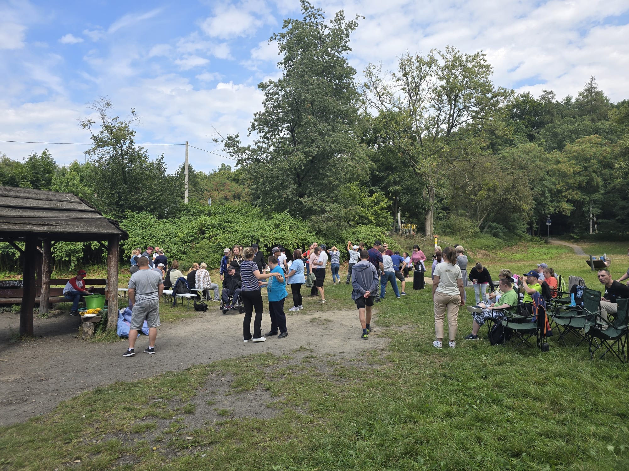 Grupa osób stoi przy ognisku.