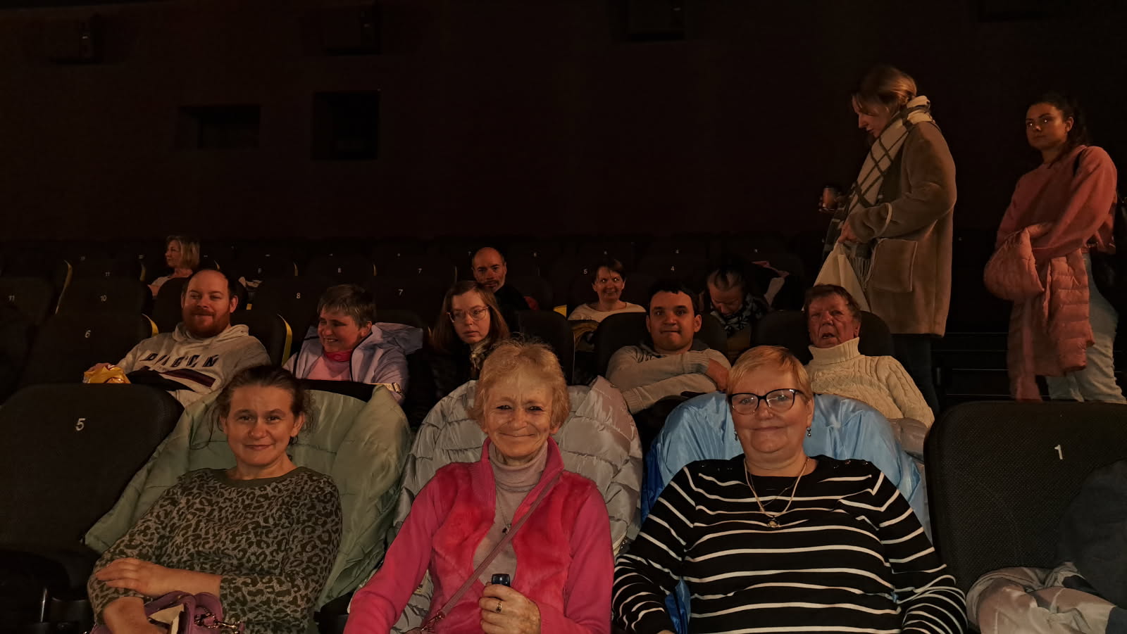 Grupa osób siedzi w sali kinowej.