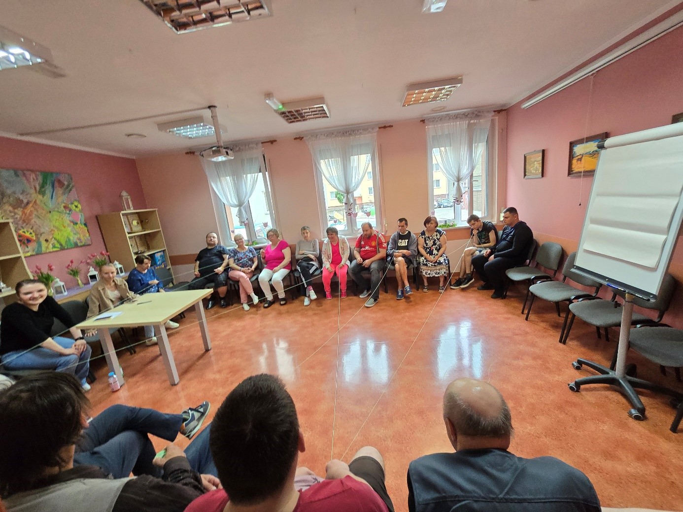Grupa osób siedzi w kręgu.
