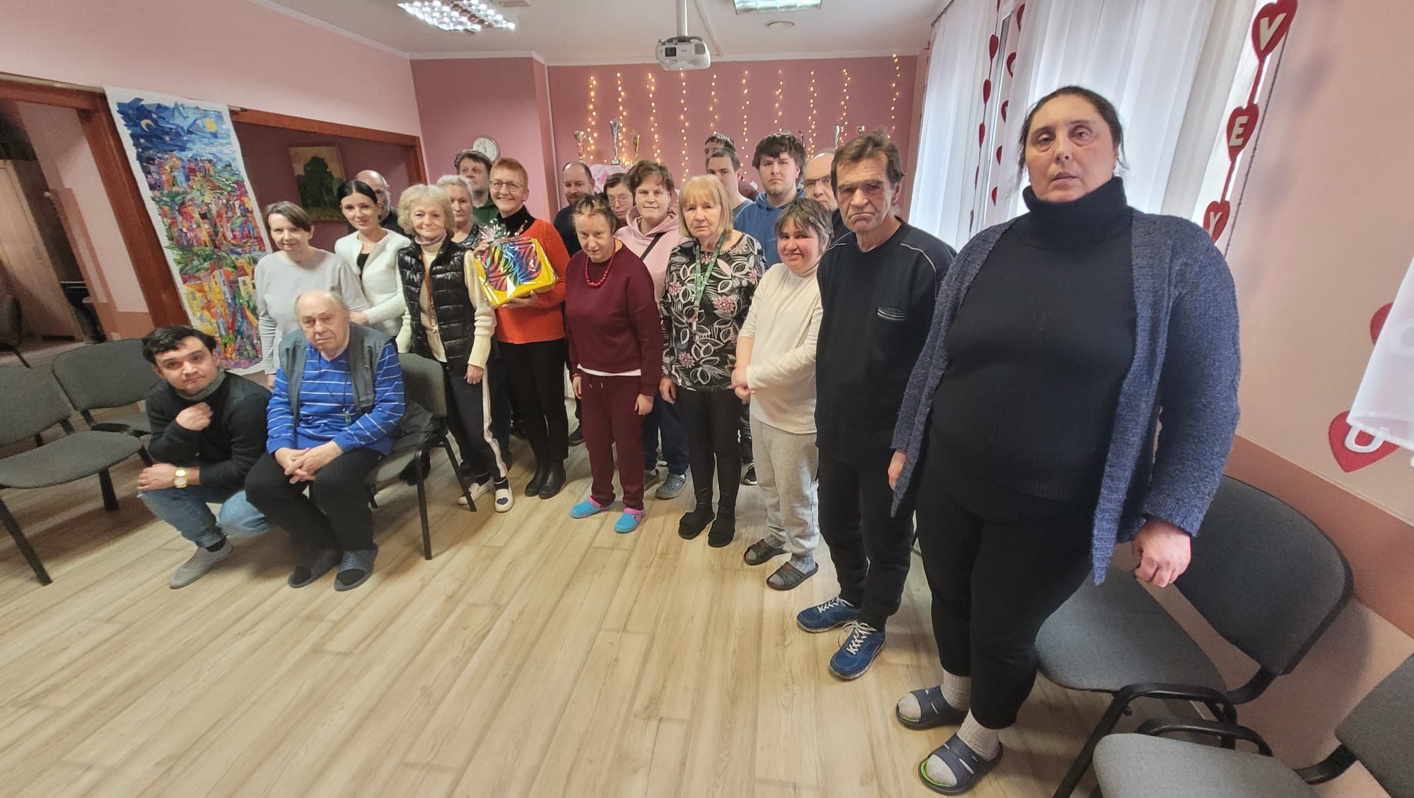 Grupa osób pozuje do wspólnego zdjęcia z autorką przedstawianych prac z różnych materiałów - patchwork.