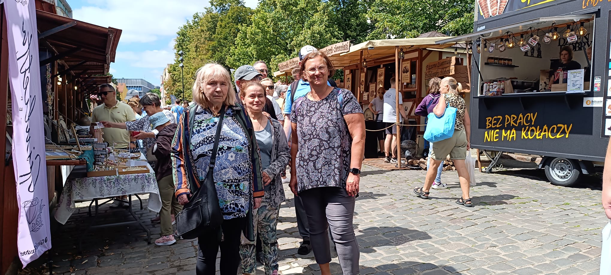 Grupa kobiet pozuje do zdjęcia na tle straganów i Katedry Szczecińskiej .