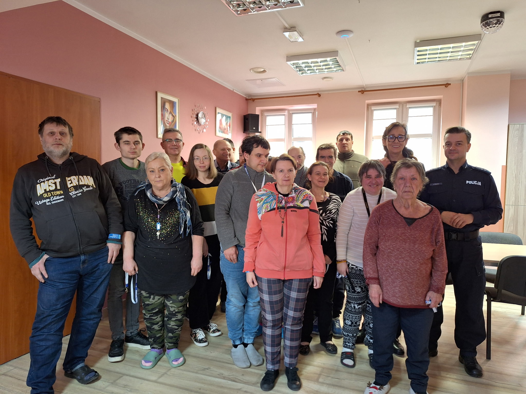 Grupa osób pozuje do pamiątkowego zdjęcia z dwójką oficerów policji w mundurach Wszyscy stoją w grupie.