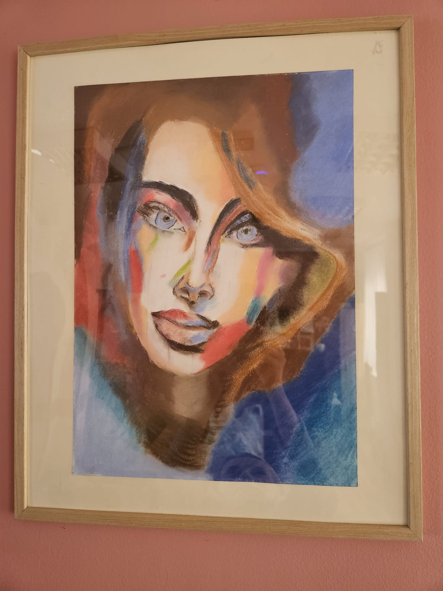 Portret młodej kobiety namalowany pastelami w drewnianej ramce za szkłem.