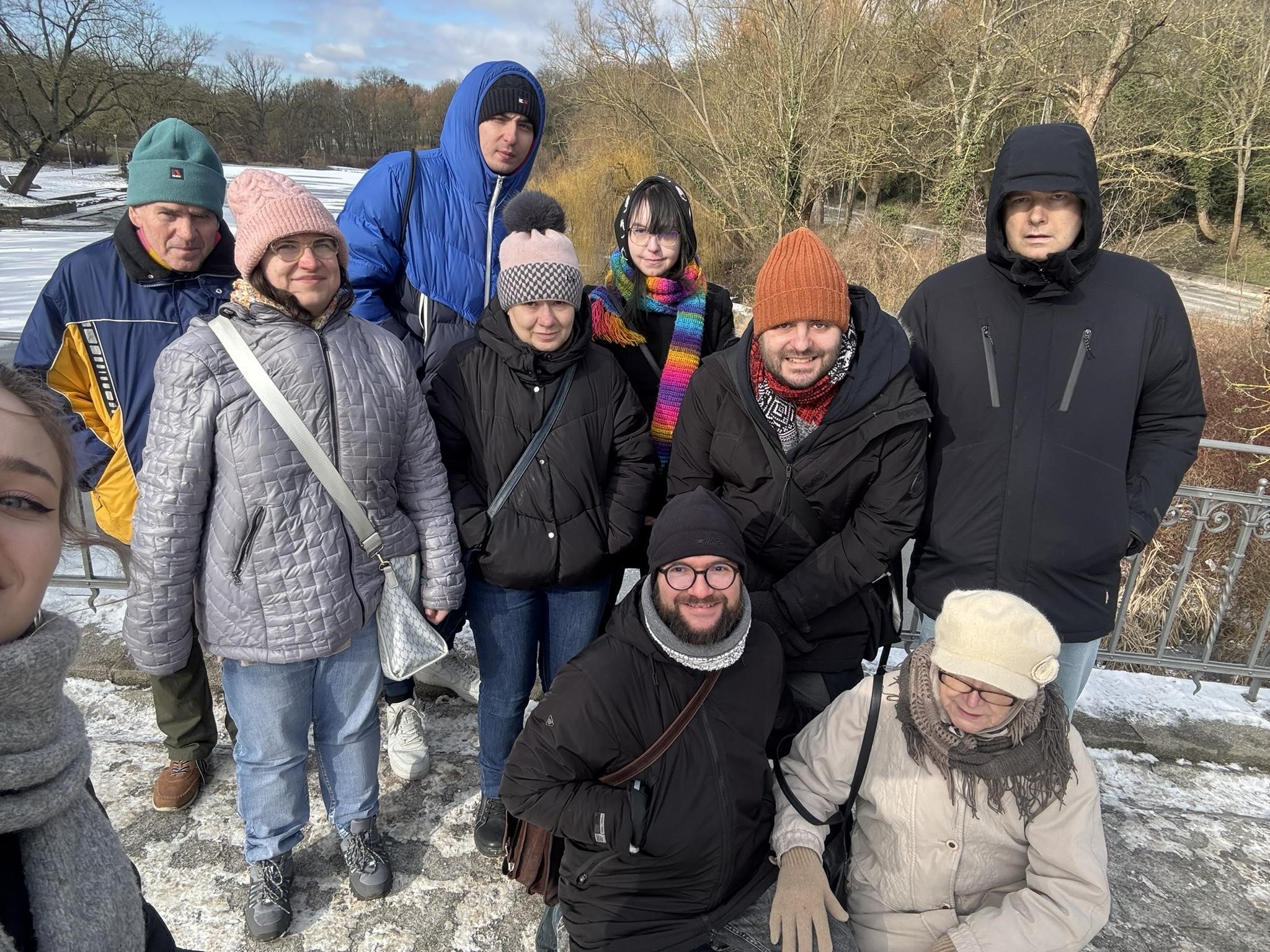 Grupa osób pozująca do zdjęcia. W tle widać drzewa oraz leżący śnieg.