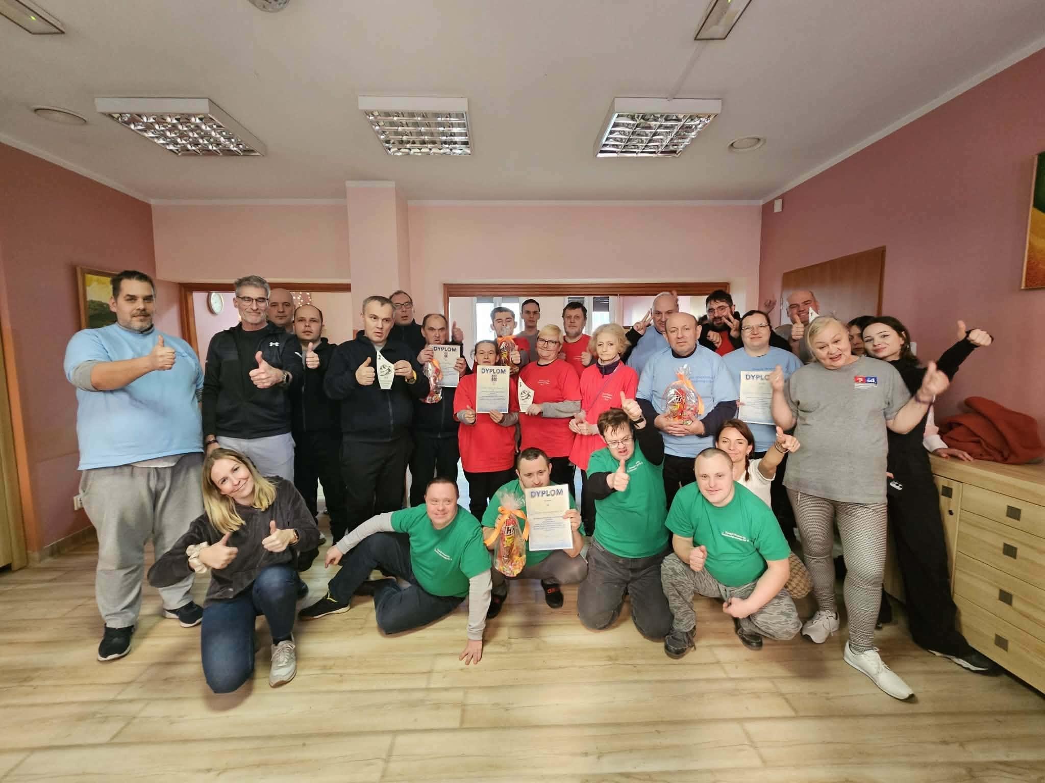 Grupa ludzi pozująca do wspólnego zdjęcia, w tle różowe ściany.