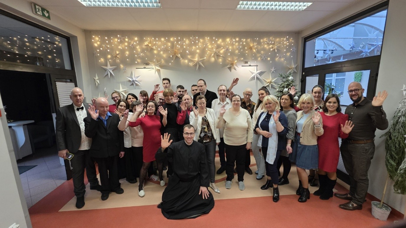 Grupa osób pozująca do zdjęcia na tle dekoracji świetlnej. 