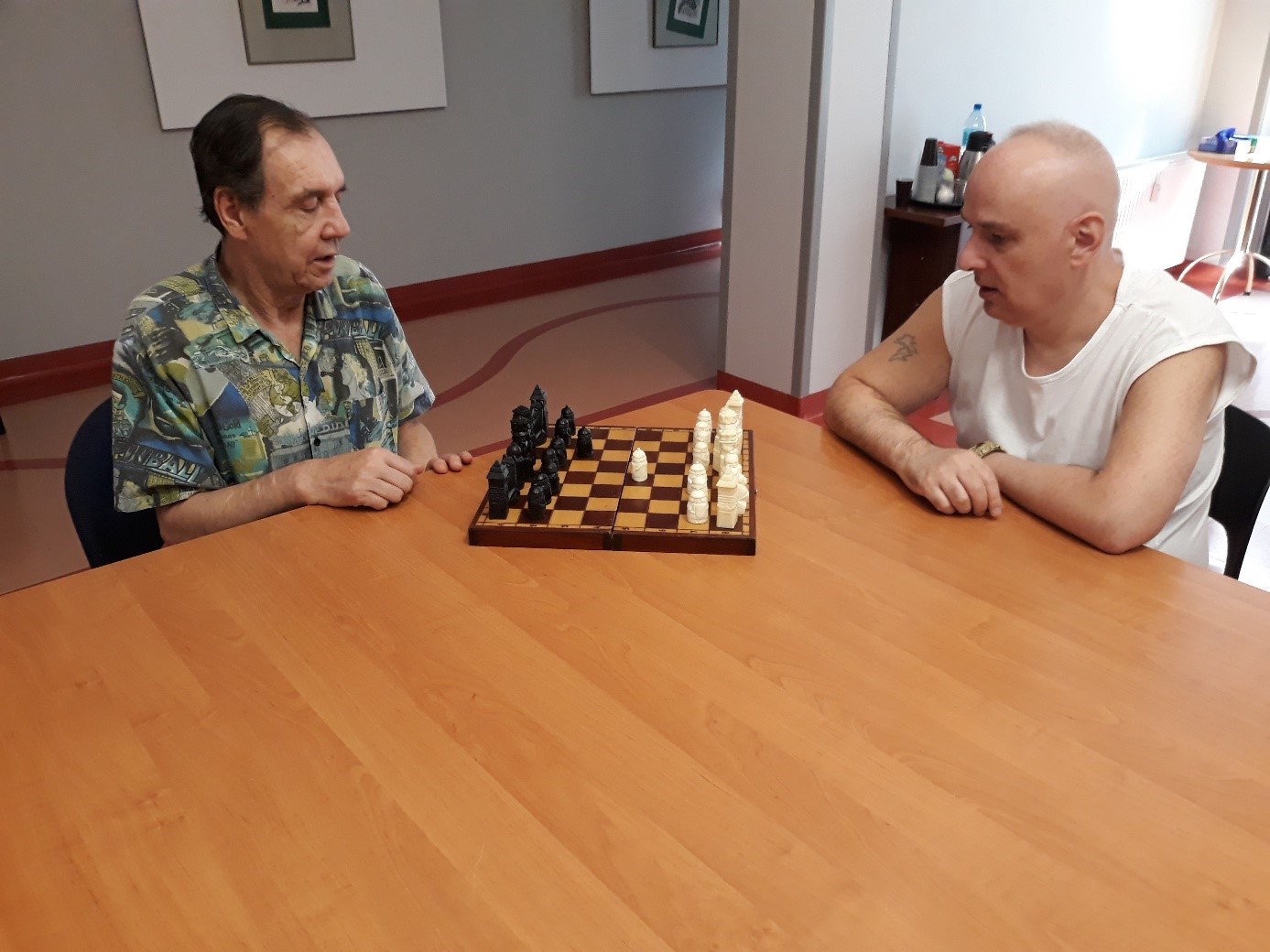 Dwóch mężczyzn siedzących przy stole i grających w szachy. 