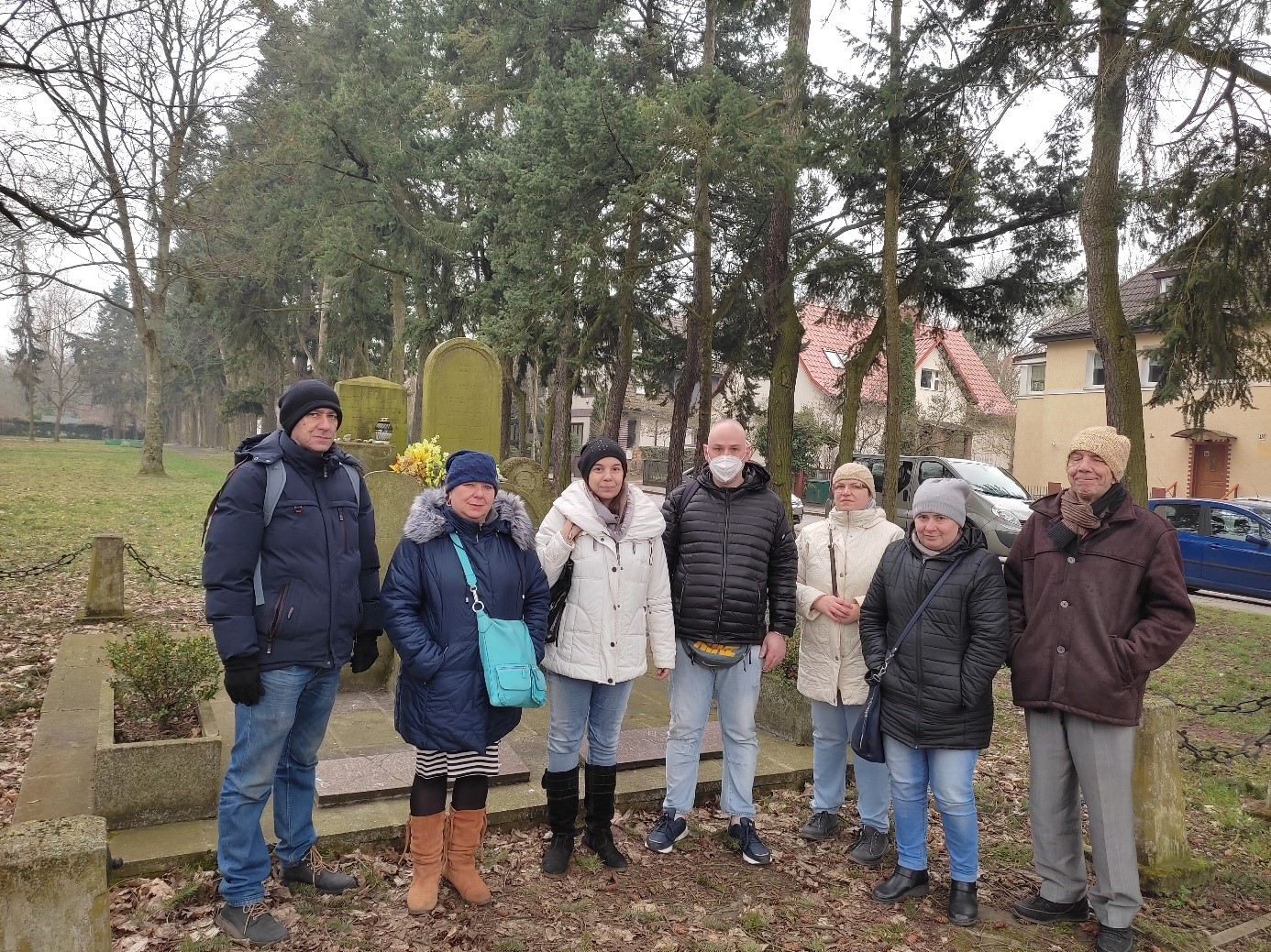 Grupa kobiet i mężczyzn na tle pomnika na dawnym cmentarzu żydowskim  w Szczecinie.