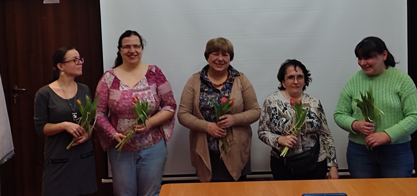 Grupa pięciu kobiet pozuje do zdjęcia z bukietami tulipanów.