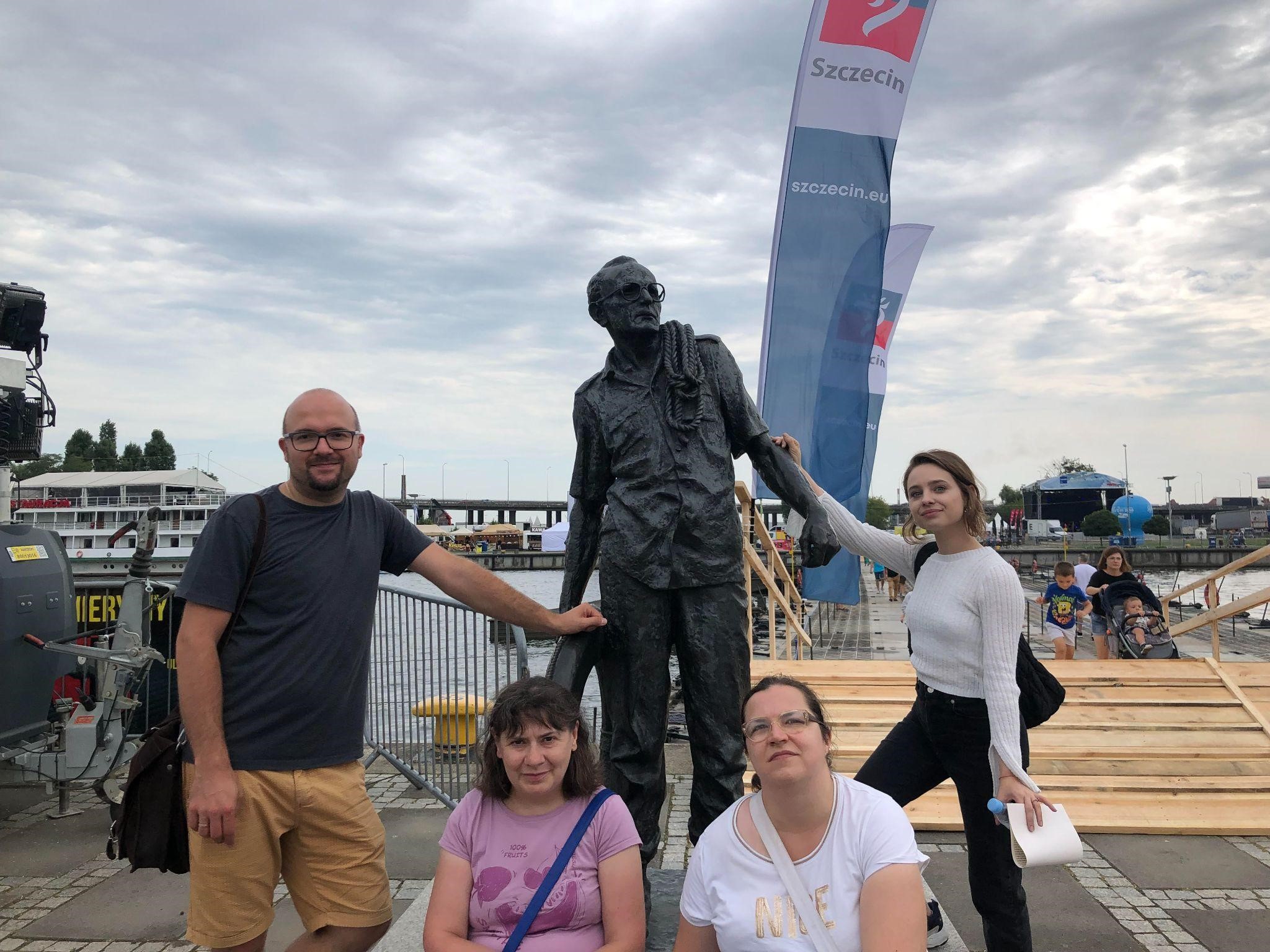 Mężczyzna oraz trzy kobiety pozujące z rzeźbą marynarza na Festiwalu Żagle 2023