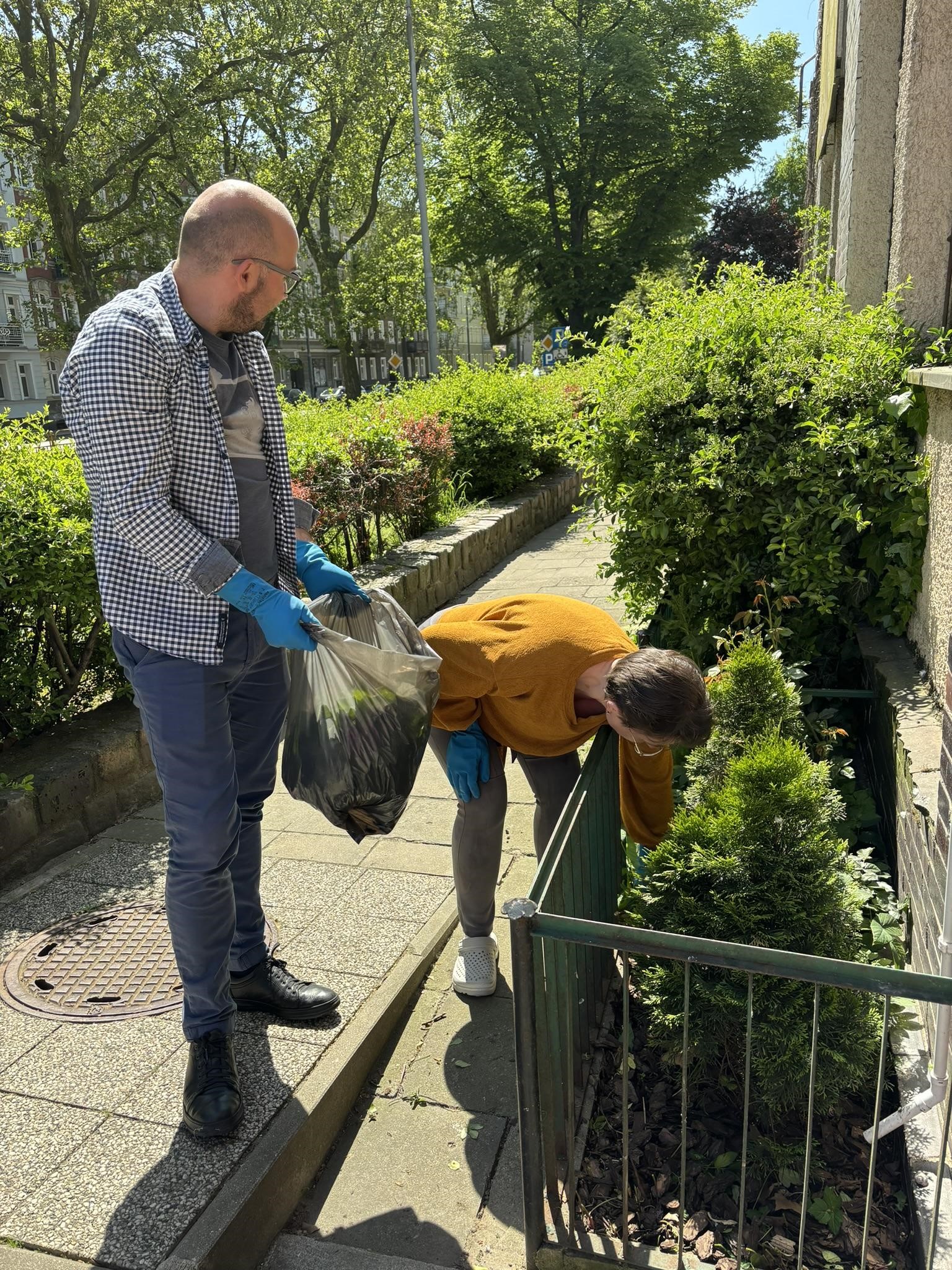 Dwie osoby wykonujące prace porządkowe terenów zielonych.