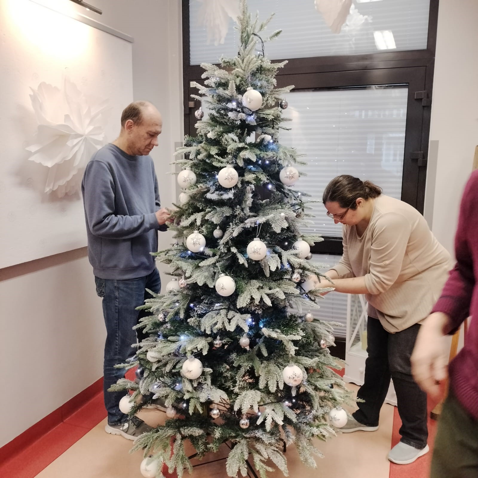 Kobieta i mężczyzna dekorujący choinkę na Święta Bożego Narodzenia. 