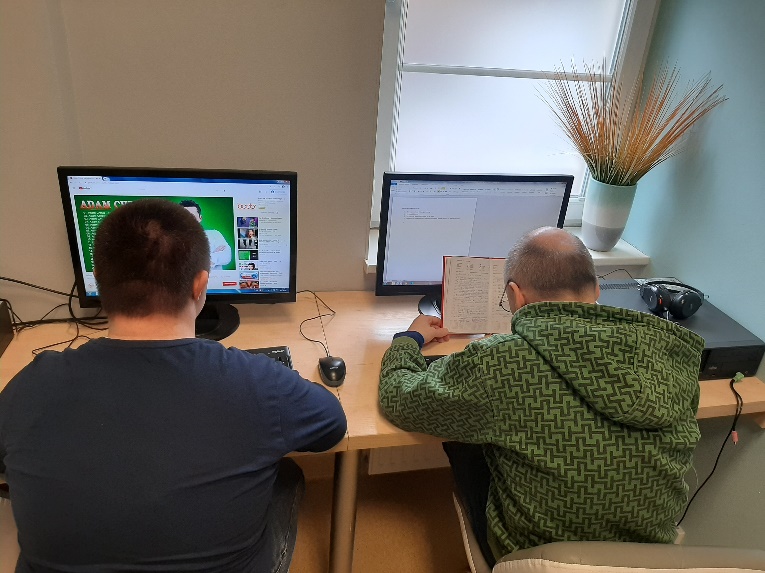 Dwóch mężczyzn siedzących tyłem przed ekranami komputerów.