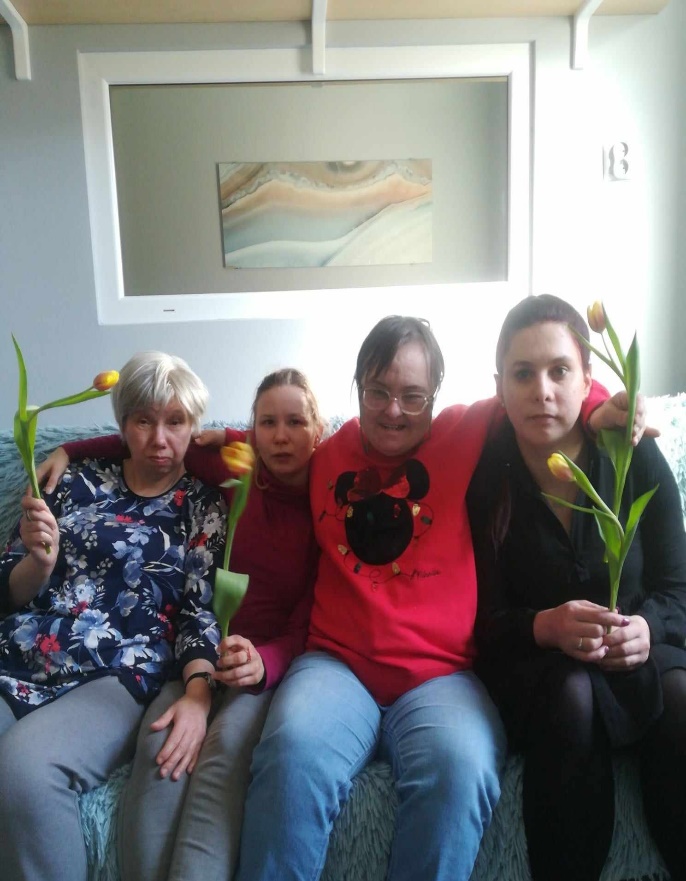 Cztery kobiety siedzą na kanapie i trzymają rękach tulipany