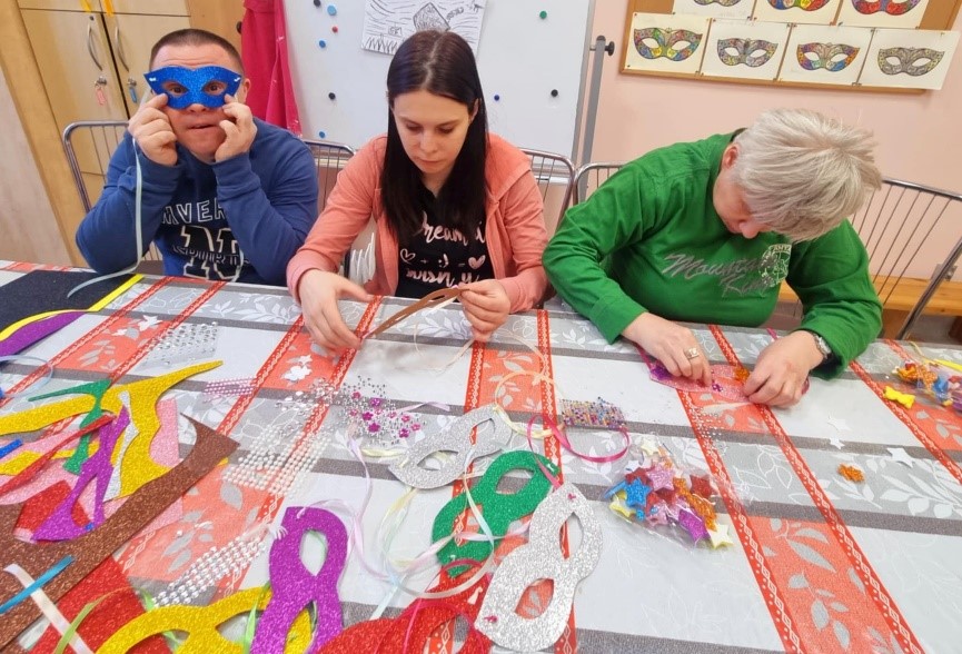 Grupa kobiet i mężczyzn wykonująca samodzielnie maski karnawałowe.