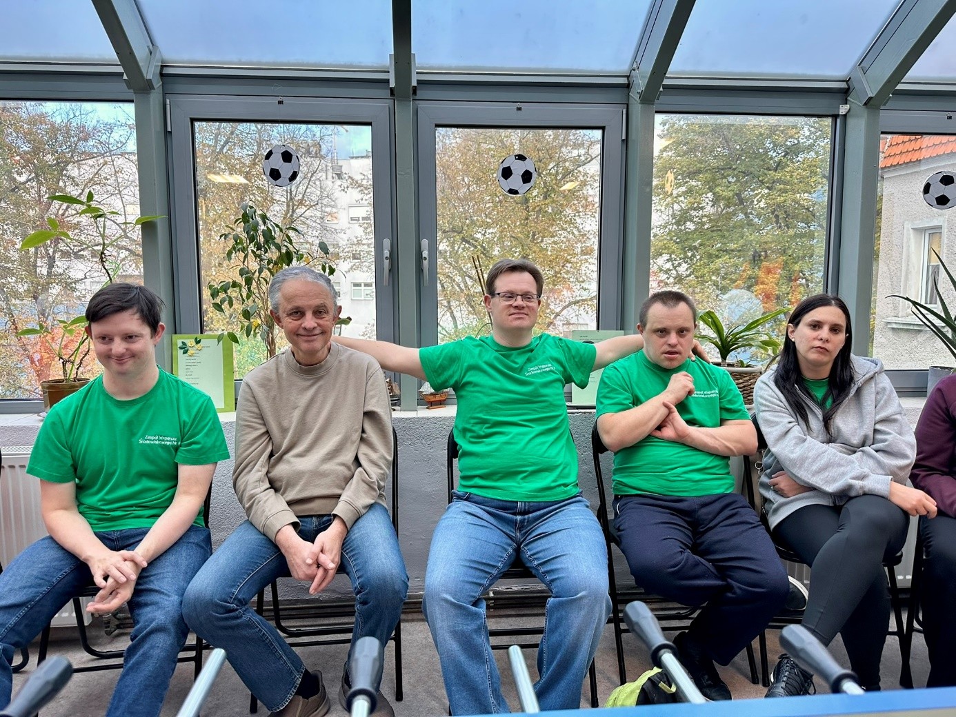 Czterech mężczyzn i jedna kobieta siedząc na krzesłach pozują do zdjęcia. 