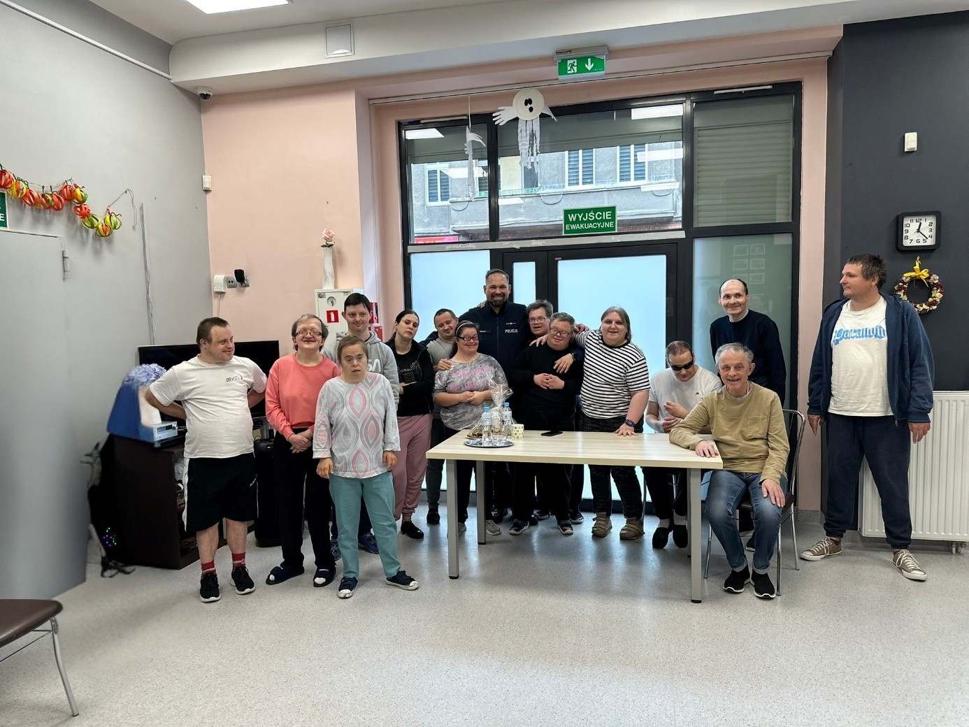 Grupa kobiet i mężczyzn pozuje do zdjęcia wraz z policjantem. 