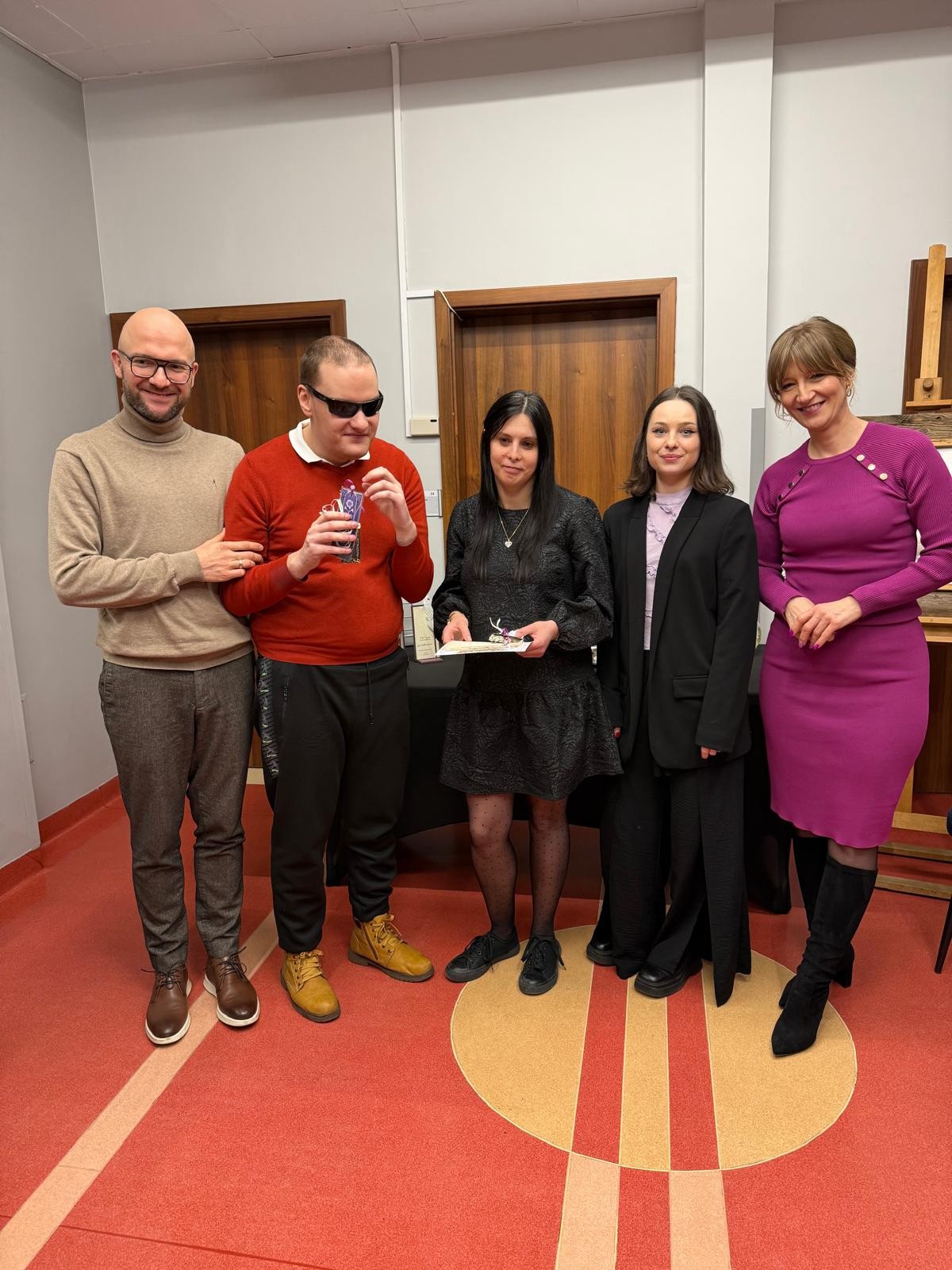 Dwóch mężczyzn i trzy kobiety stoją obok siebie, uśmiechają się i patrzą prosto w obiektyw. 