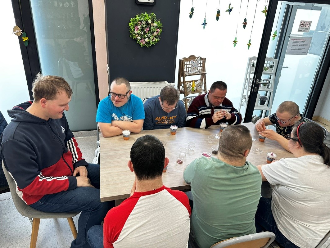 Grupa osób siedzi przy stole. 